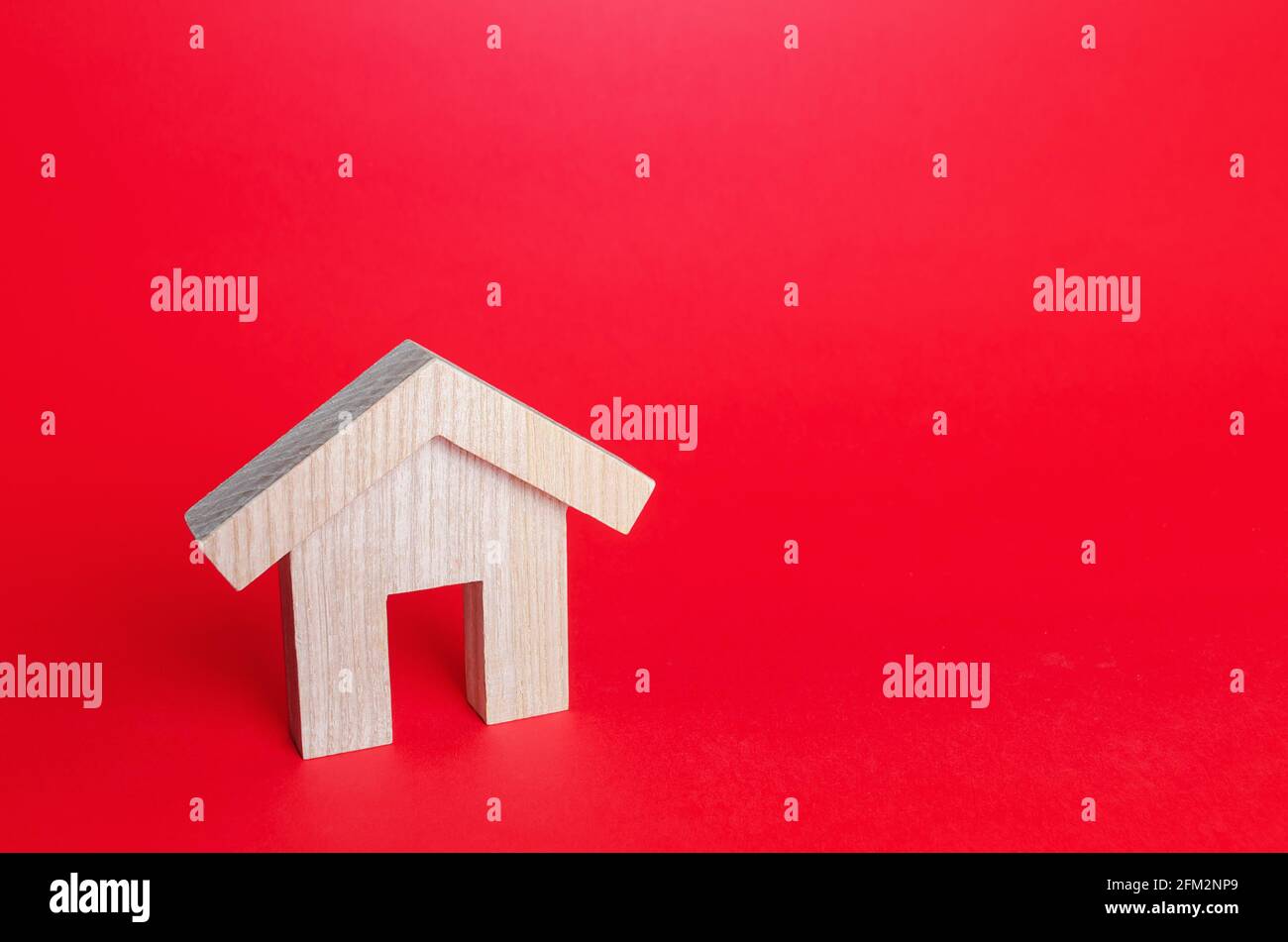 Wooden house on a red background. Buying and selling. Housing, realtor services. Renovation and home improvement. Building maintenance. Rent of apartm Stock Photo