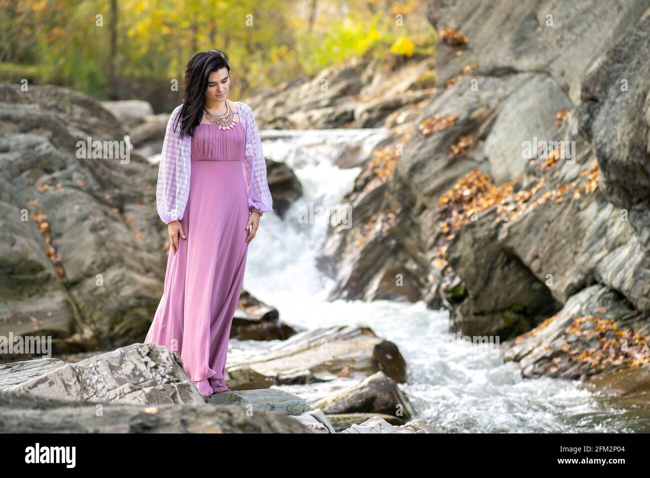 Young pretty woman in long pink fashionable dress standing near small ...