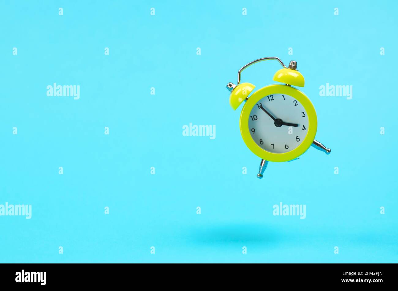 Yellow retro alarm clock levitates. Alarm clock in the old style on a