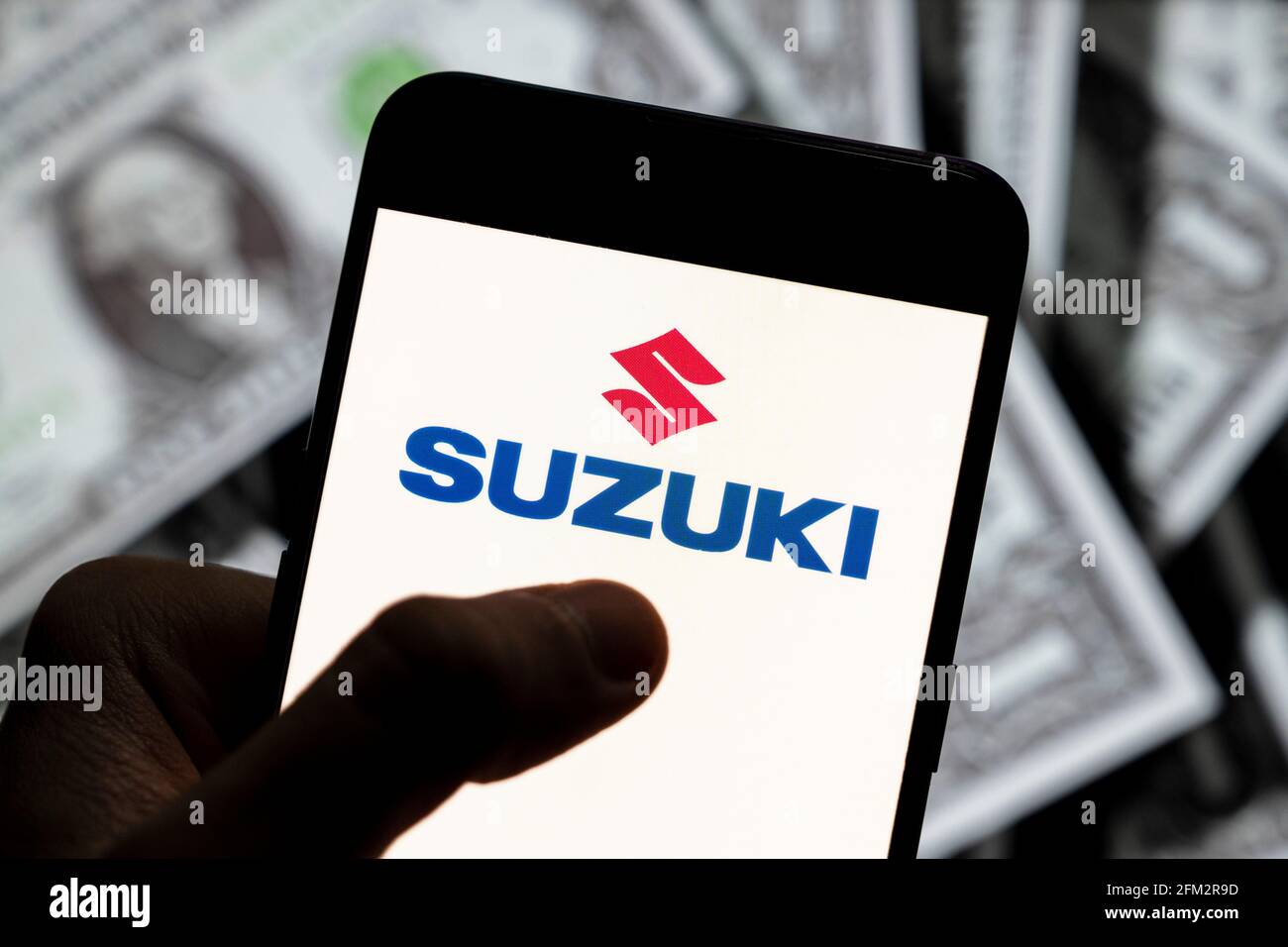 In this photo illustration the Japanese multinational automobile manufacturer Suzuki logo seen displayed on a smartphone with USD (United States dollar) currency in the background. (Photo by Budrul Chukrut / SOPA Images/Sipa USA) Stock Photo