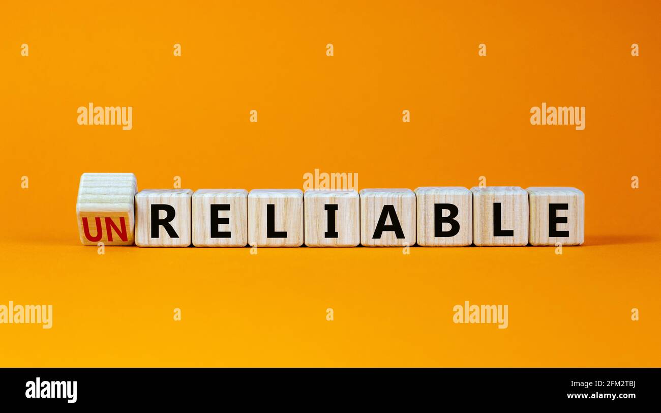 Unreliable or reliable symbol. Turned wooden cubes and changed the word unreliable to reliable. Beautiful orange background, copy space. Business and Stock Photo