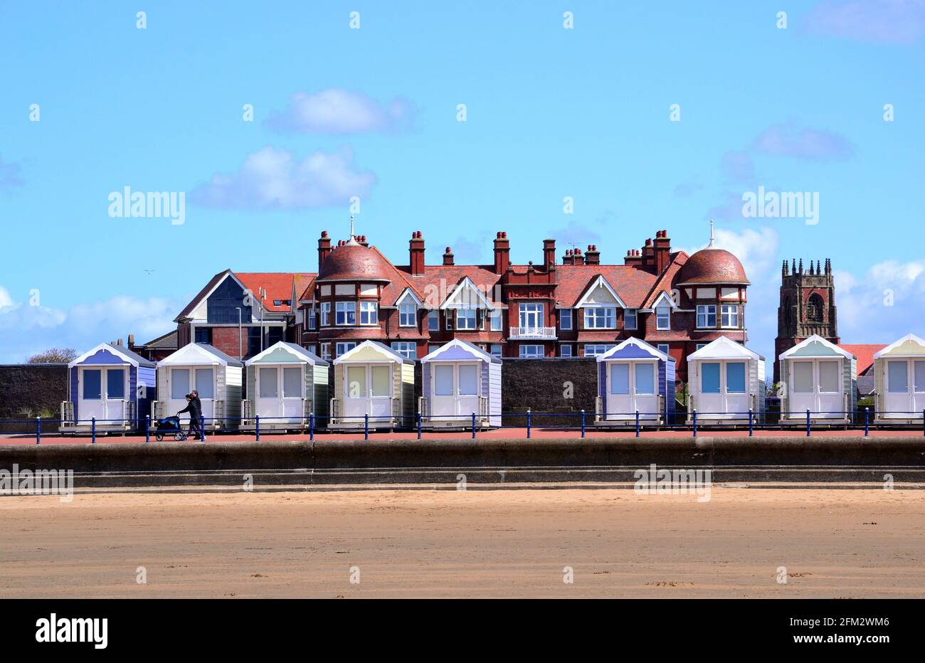 Sand in front of a row of beach huts in the sunshine at St Annes On Sea