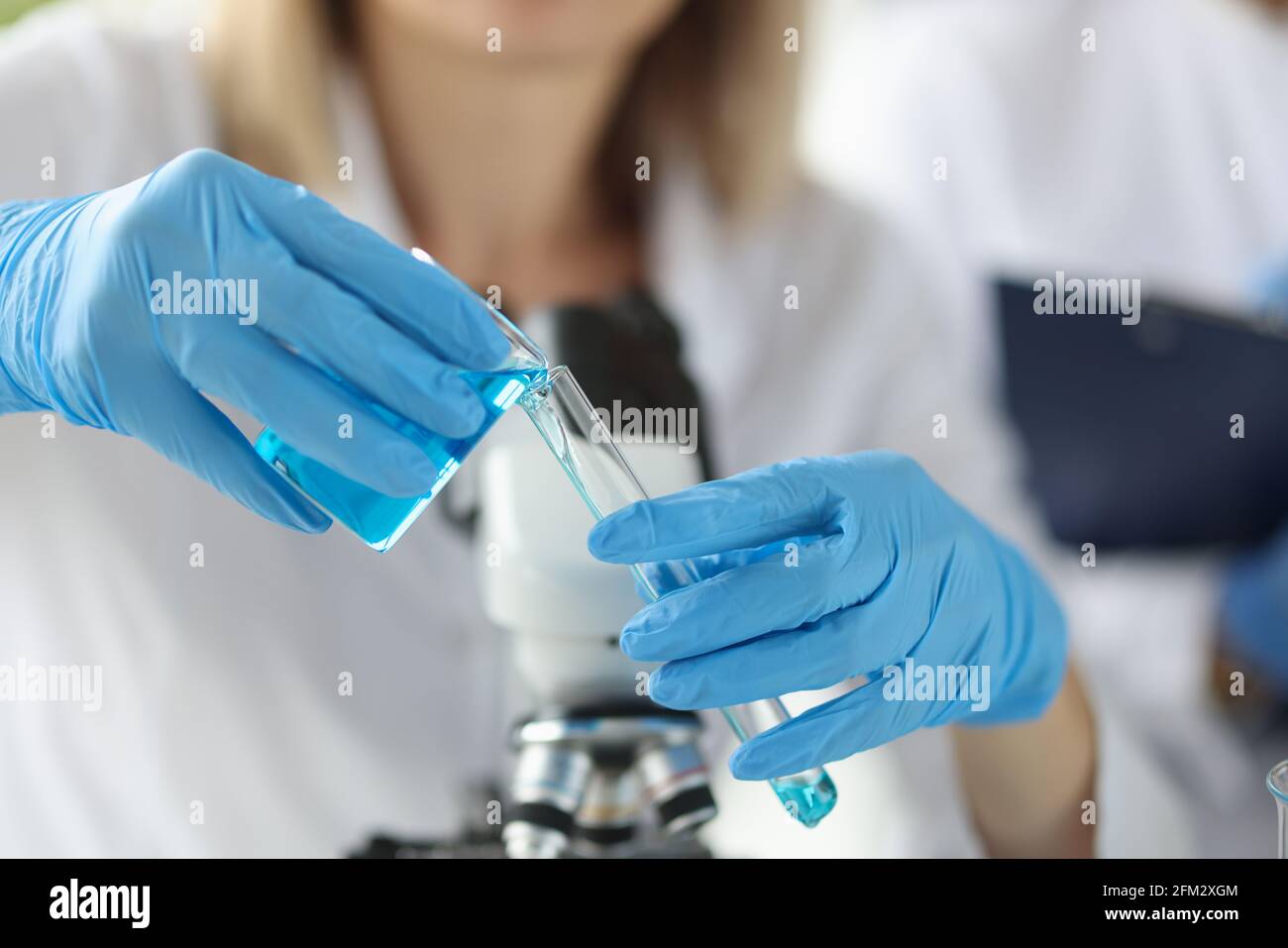 Hands of scientist in gloves pouring blue liquid into test tube Stock ...