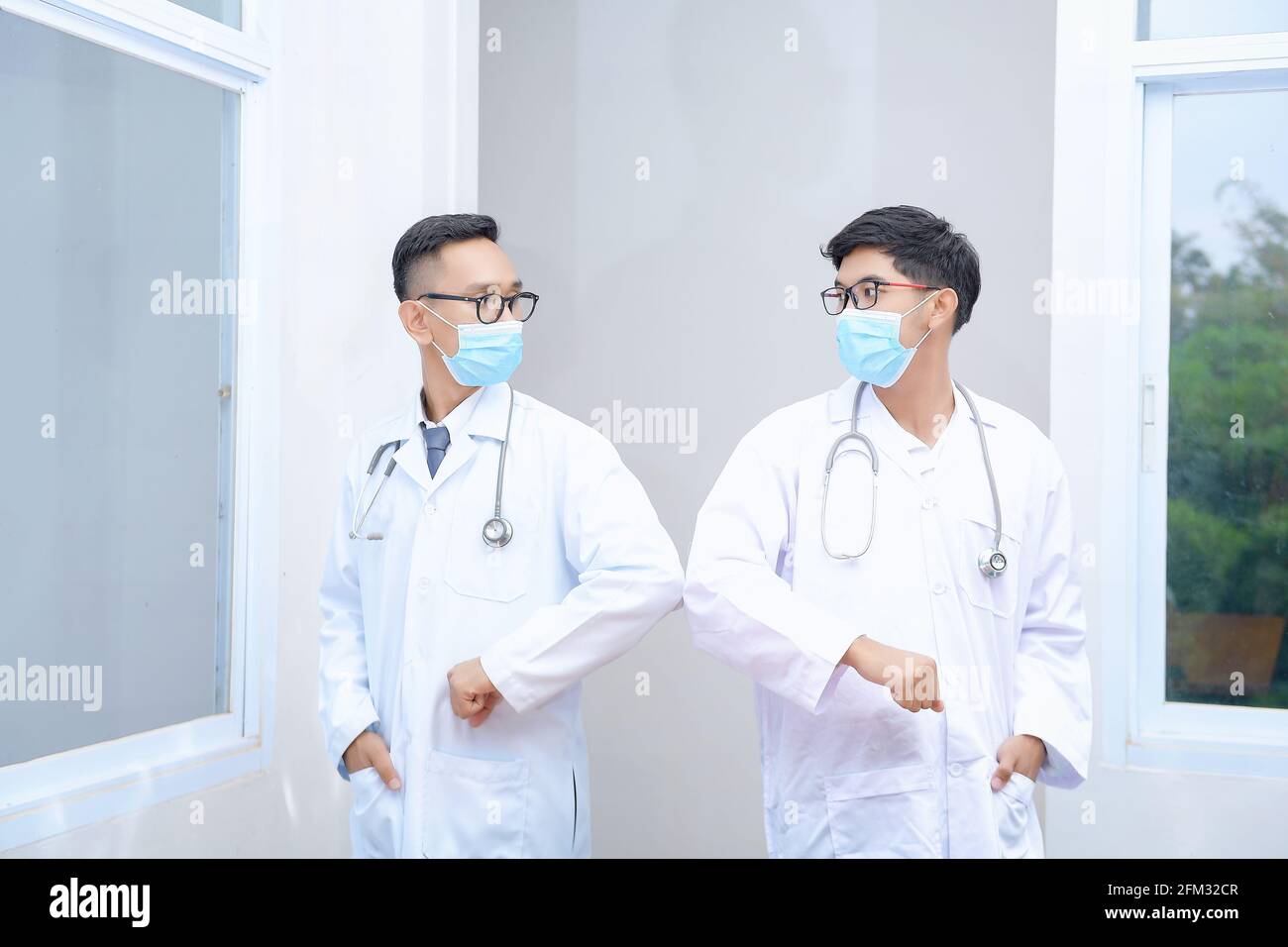 Portrait of two doctors greeting each other by bumping elbows Stock Photo
