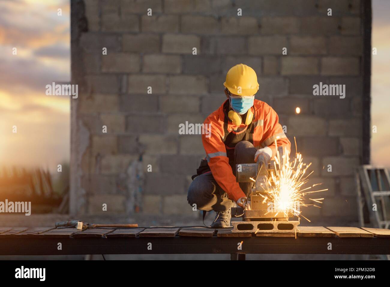 Construction worker using an electric saw on a building site, Thailand Stock Photo