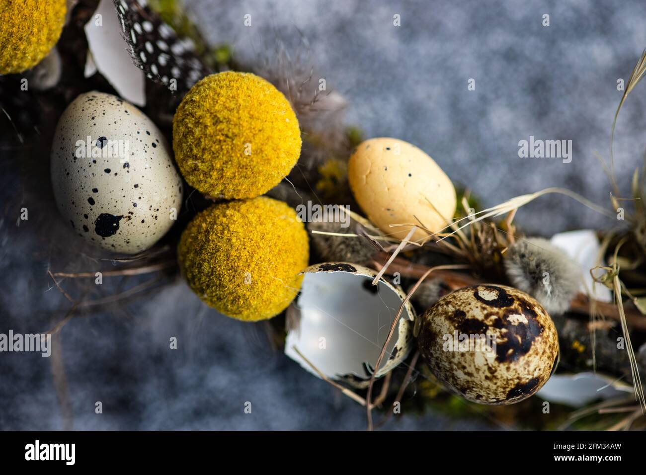 Close-Up of an Easter wreath decorated with quail eggs and feathers on a table Stock Photo