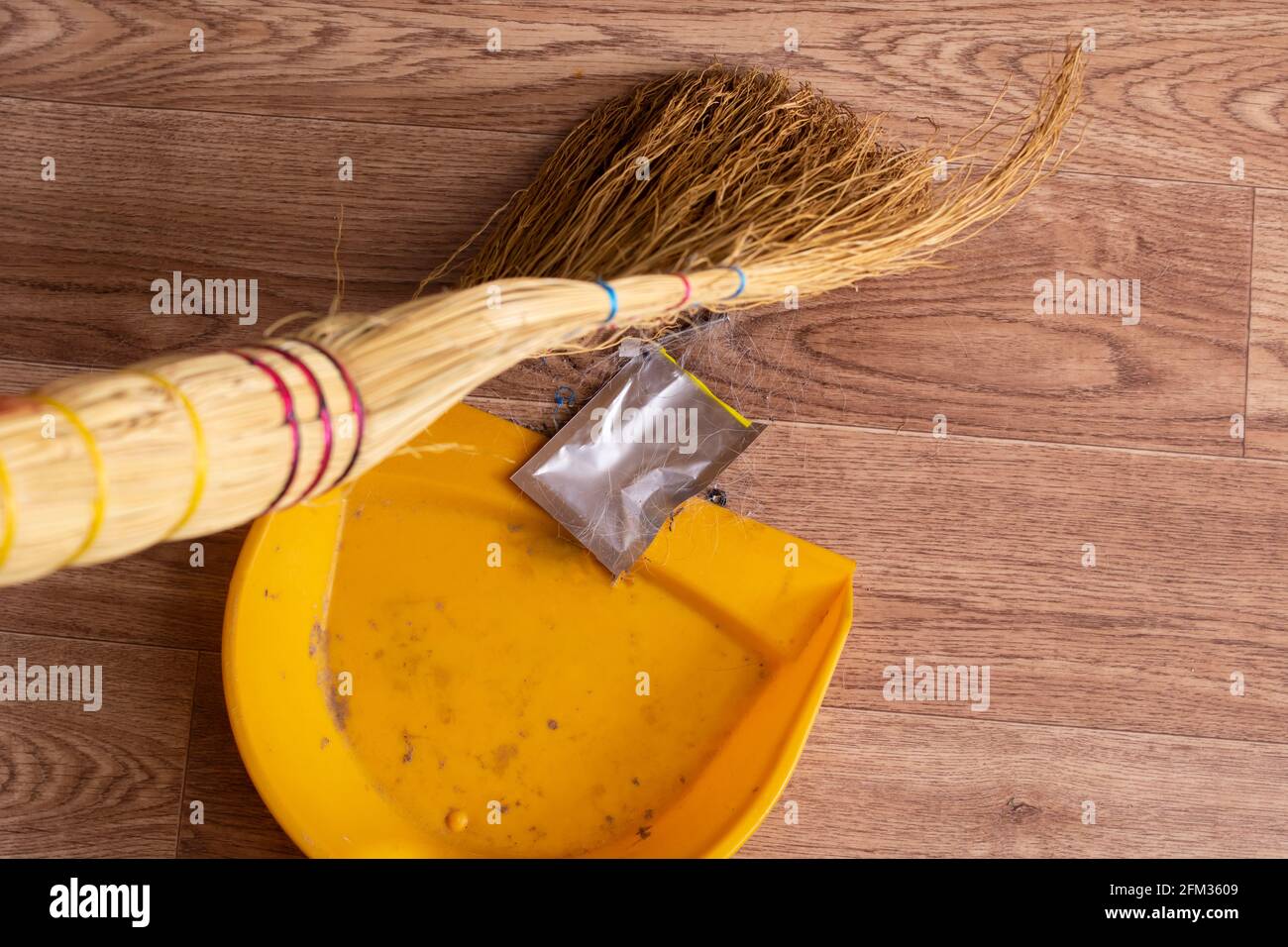 Broom and scoop removes garbage on wooden floor close up Stock Photo