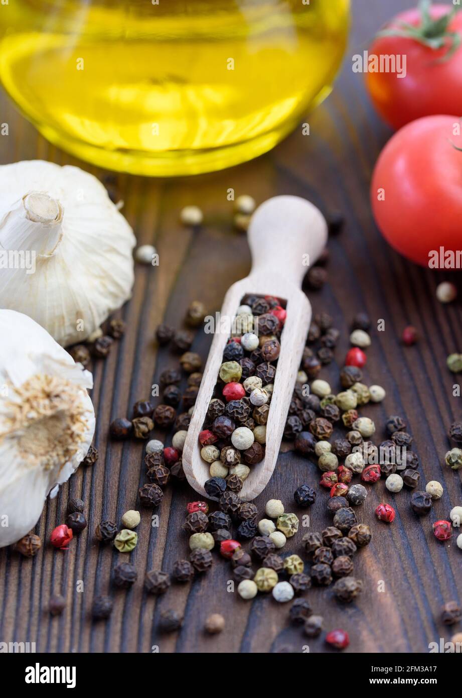 Close-up of mixed peppercorns on a table with garlic, tomatoes and olive oil Stock Photo