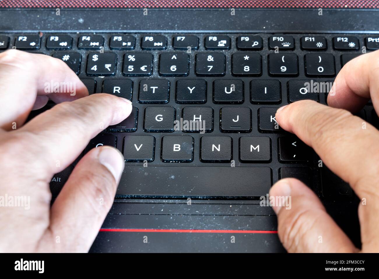 Fingers typing on laptop computer keyboard laced with dusk, particles and is very unhygienic and unhealthy Stock Photo