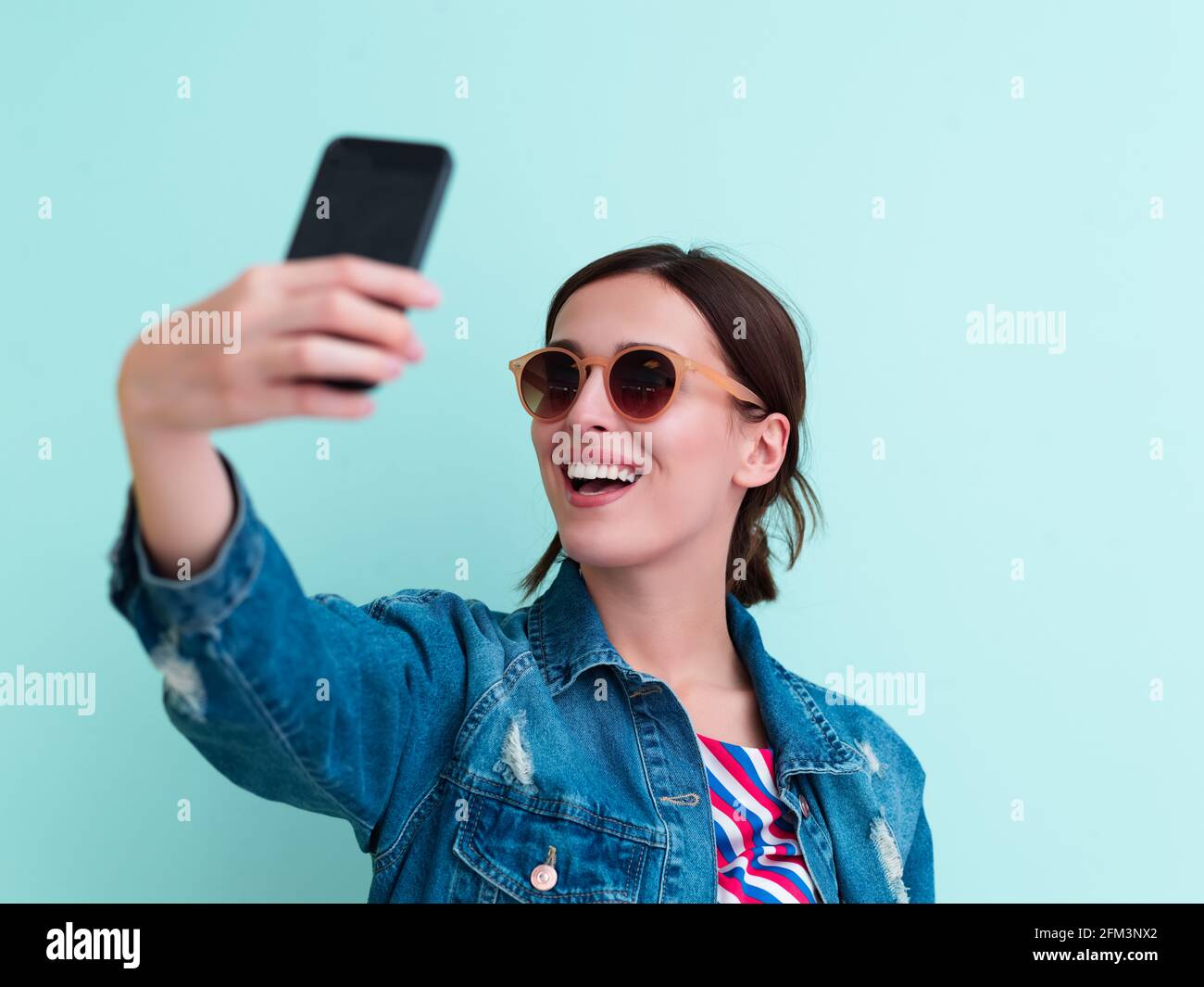 Portrait of young girl taking selfie on blue background Stock Photo - Alamy