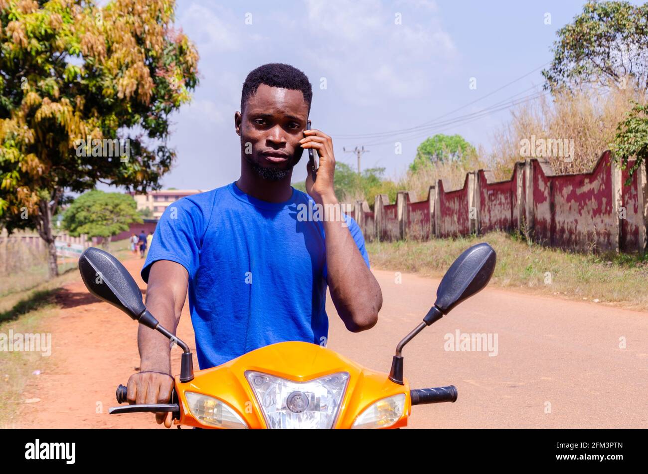 Cool African biker talking on the phone while looking at the camera on ...
