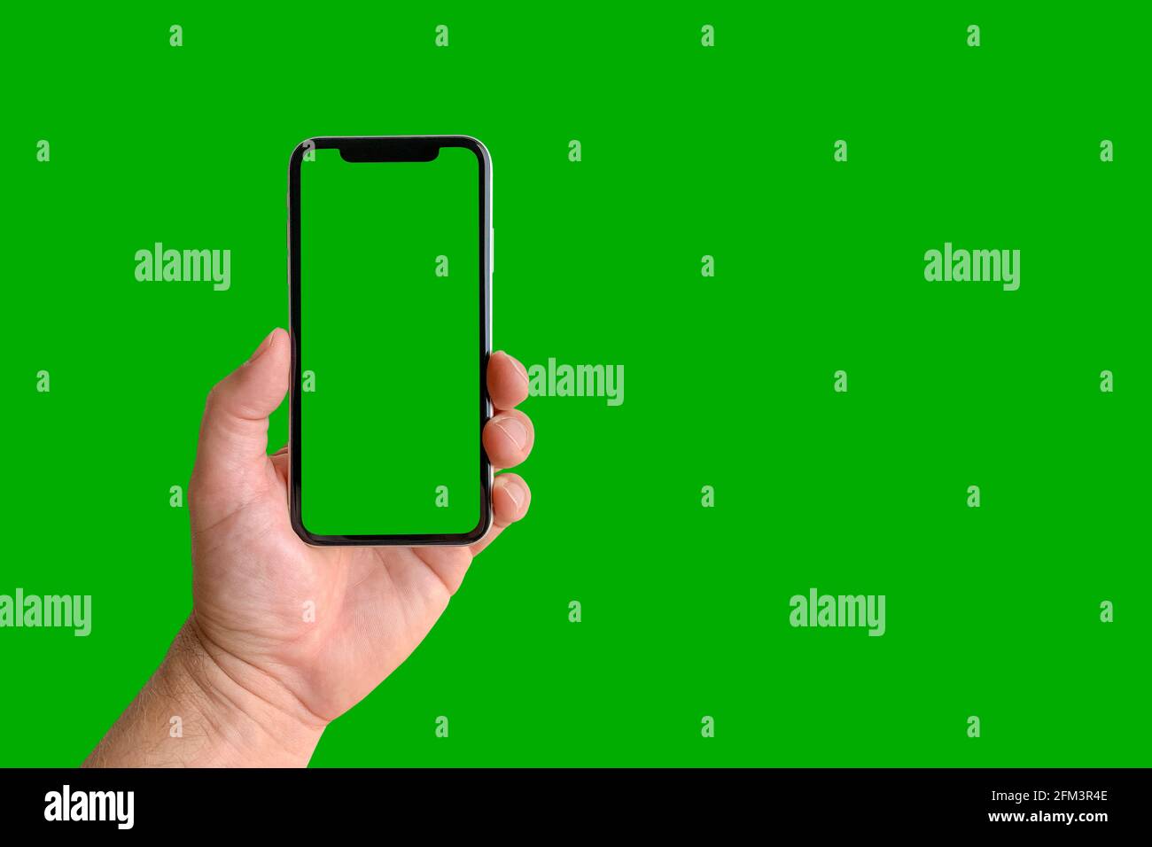 Man holding mobile phone with green screen on green background, closeup of hand. Space for text Stock Photo