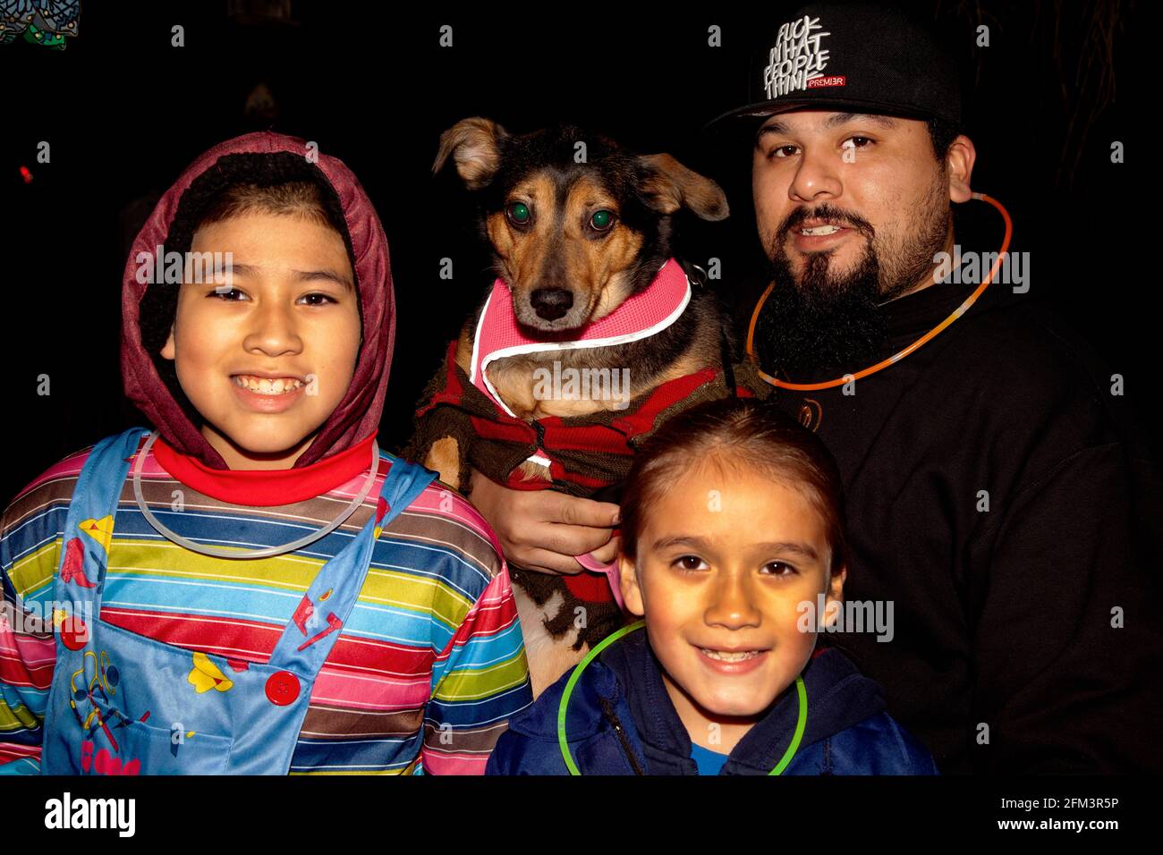 Costumed Latino family out for a night of Halloween trick or treats - sisters their dog and dad. St Paul Minnesota MN USA Stock Photo
