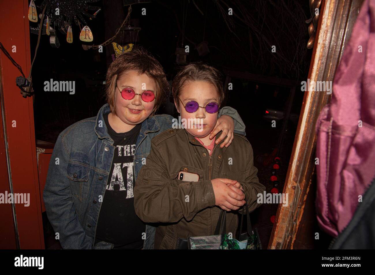 Cool looking preteen girls out trick or treating on Halloween evening wearing red and purple glasses. St Paul Minnesota MN USA Stock Photo