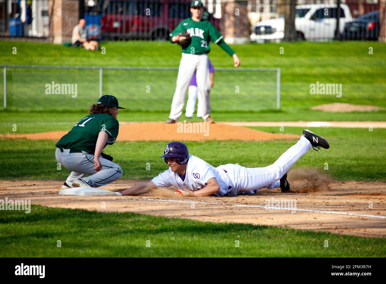 High school baseball game at Cretin Durham Hall with player sliding headfirst into third base. St Paul Minnesota MN USA Stock Photo