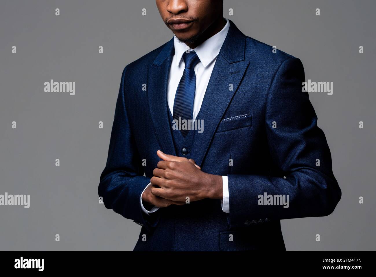 Anonymous young African man wearing formal business suit in studio gray isolated background Stock Photo