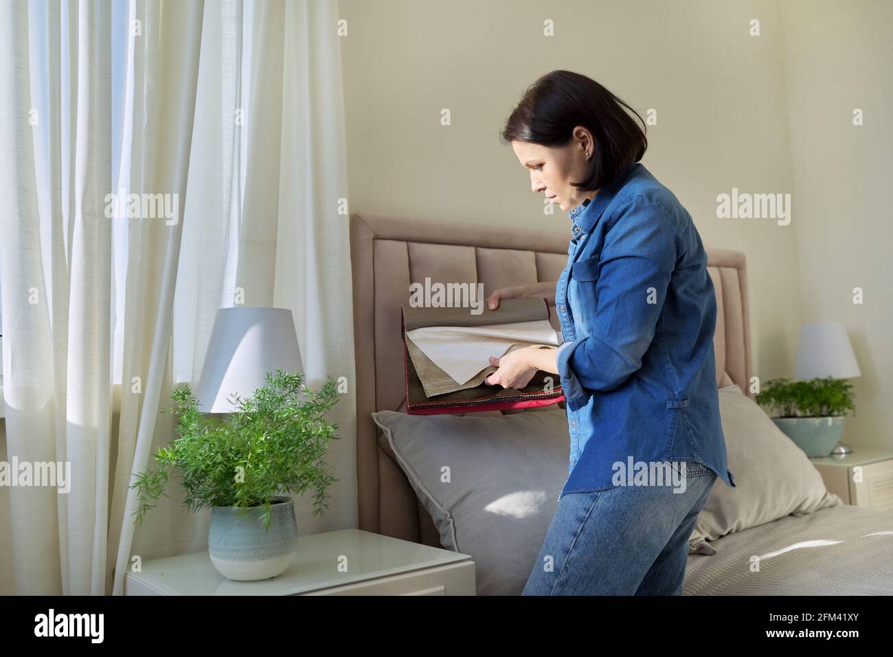 Woman with samples of interior fabrics choosing fabrics for upholstery, curtains Stock Photo
