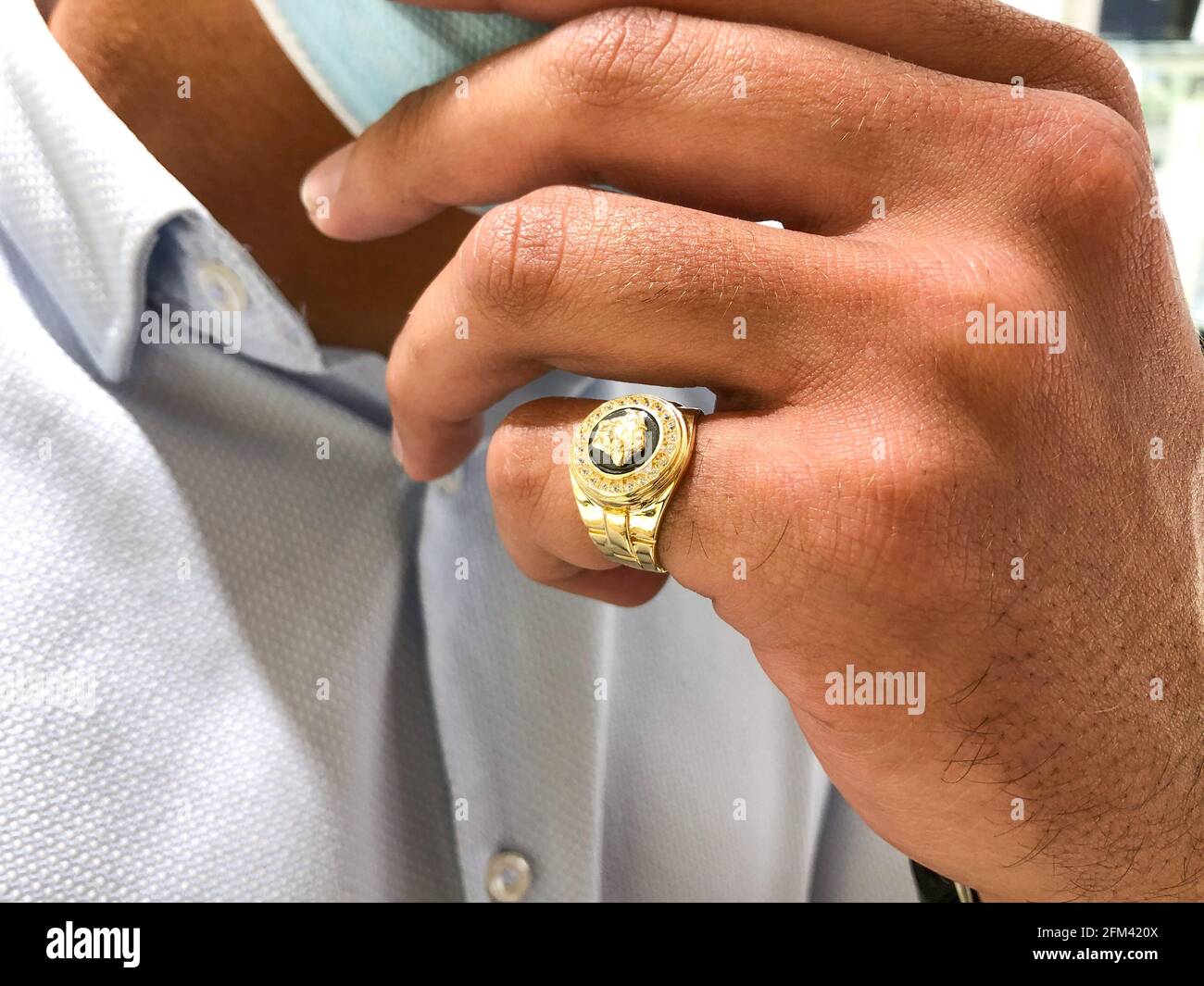 Alicante, Spain - April, 2021: Big gold Versace style ring on young man hand,  wearing face mask Stock Photo - Alamy