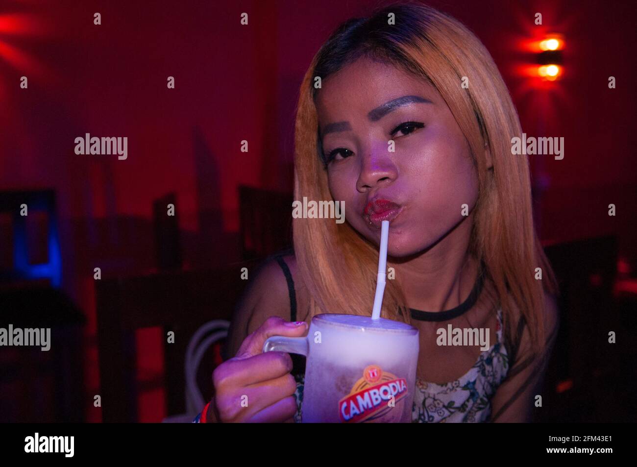 Phnom Penh nightlife. portrait of a Cambodian bar girl in a girly bar drinking an ice cold