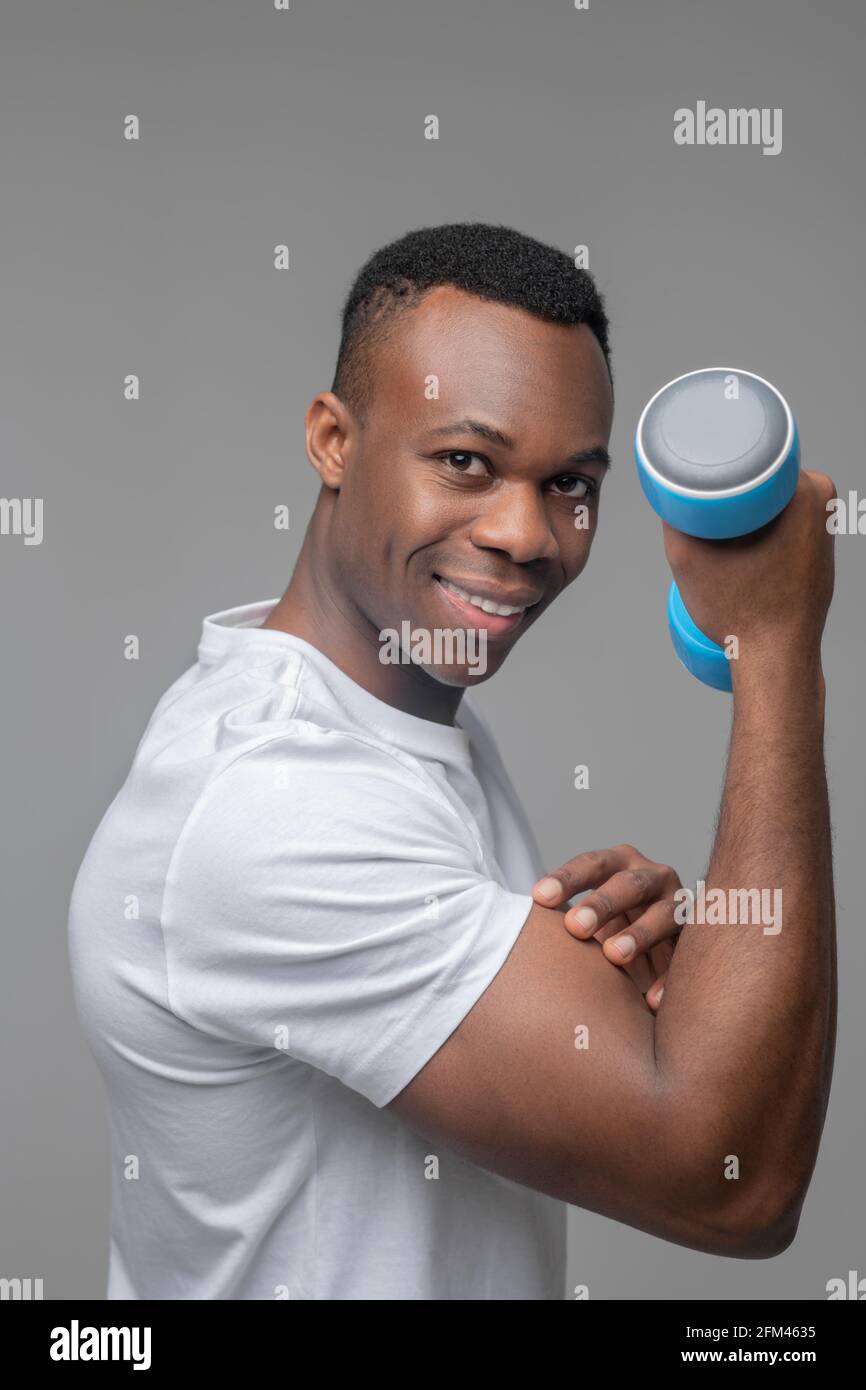 Happy man with dumbbell showing biceps Stock Photo