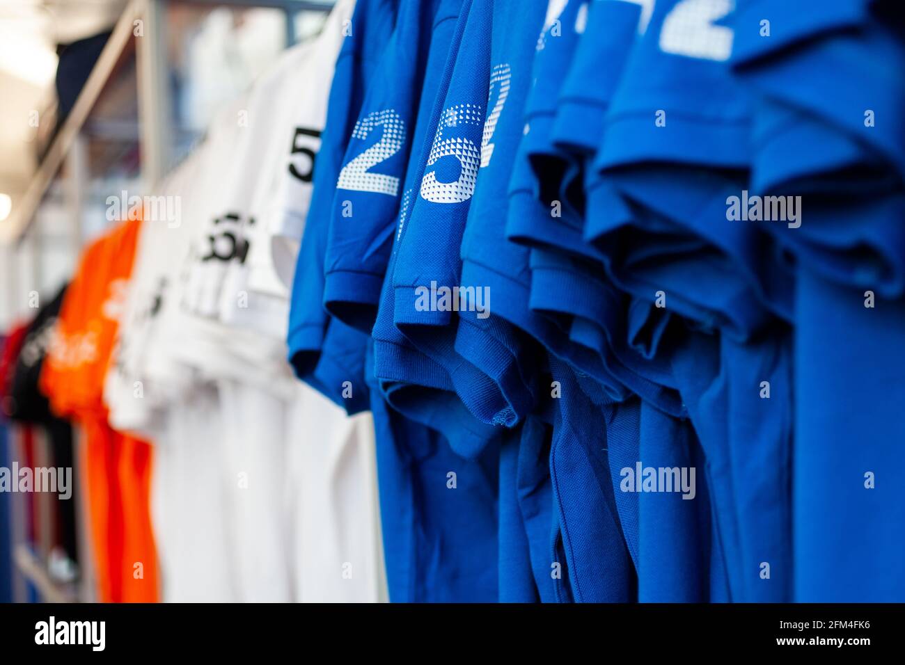 View of colorful t-shirts on hangers exposed in a clothes shop Stock Photo