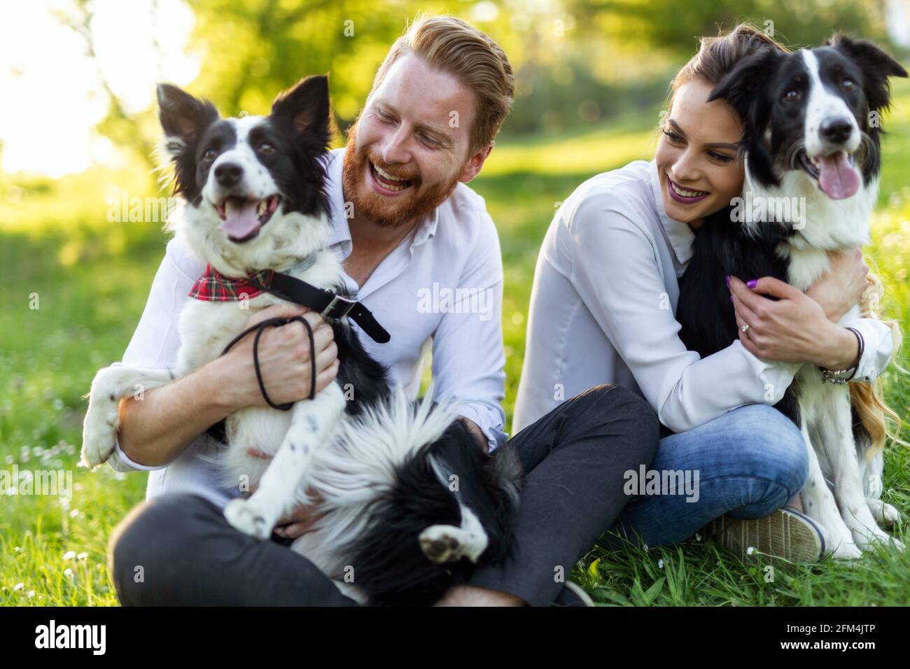 Happy couple playing with dog in the park outdoor Stock Photo - Alamy