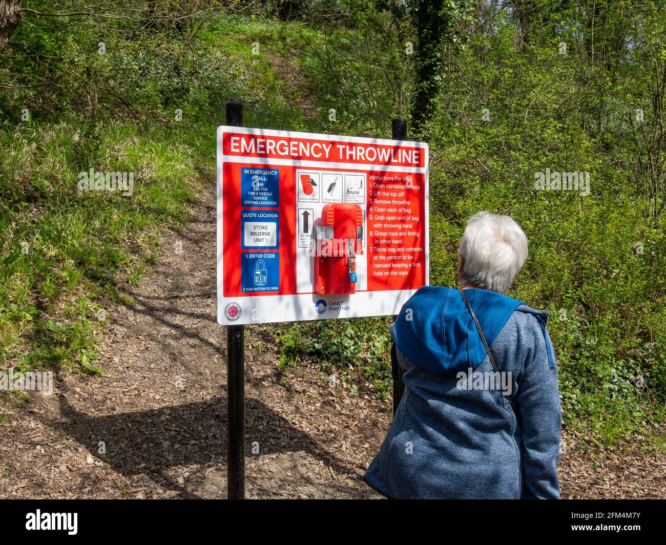 Emergency Throwline and instruction board, Grand Union canal, Stoke Bruerne, Northamptonshire, UK; woman reading board. Stock Photo