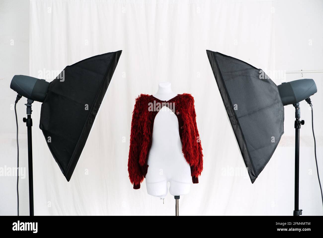 Circular Economy, Fast fashion, Sustainable fashion. Content photo session. Red knitted fashionable jacket in photo studio with Studio Flash Lighting Stock Photo