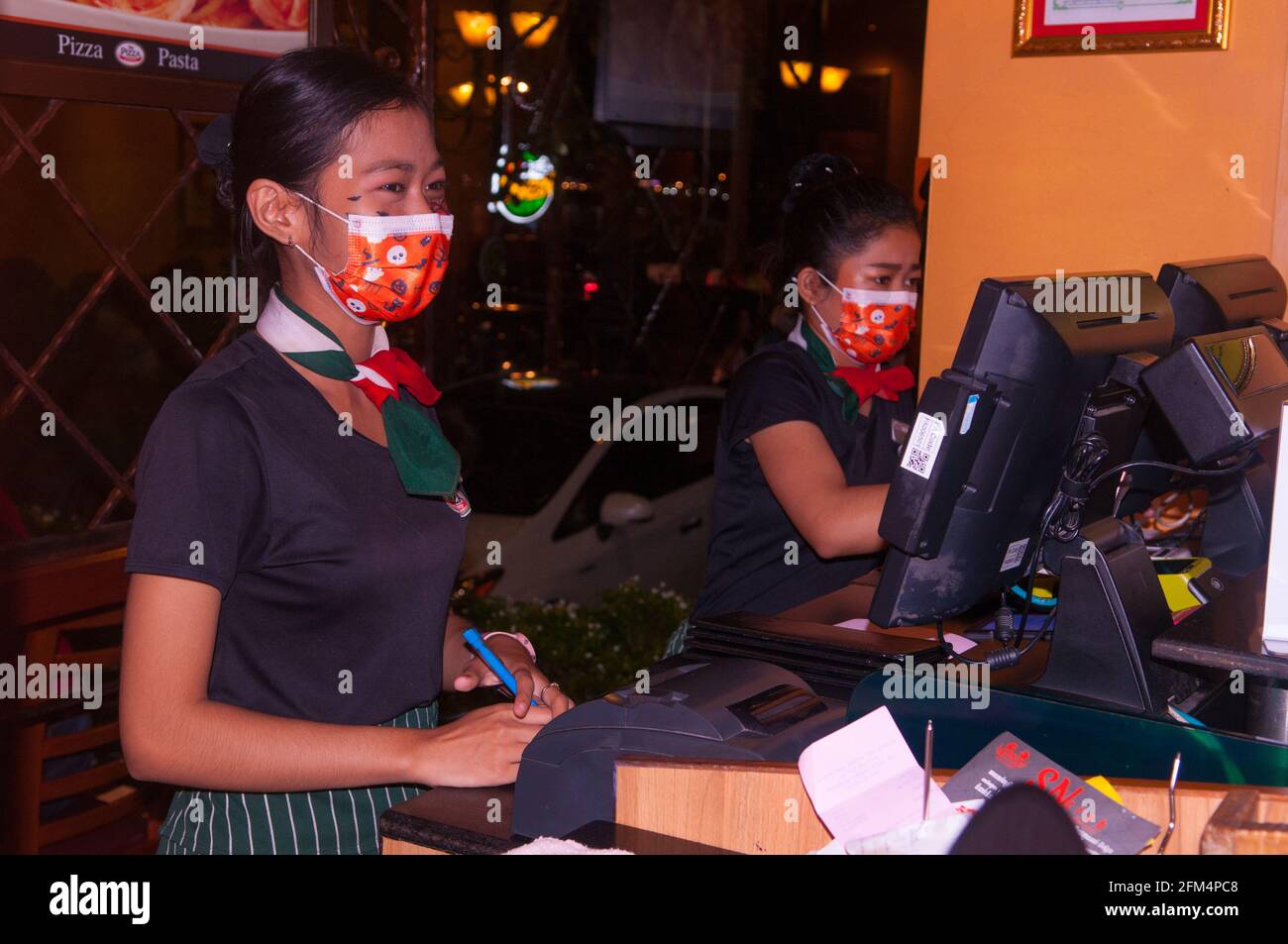 An attractive Cambodian hostess & cashier wear stylish protective face masks due to the COVID -19 pandemic during Halloween, which also coincided w/ the Water Festival this year. October 30th, 2020. Phnom Penh, Cambodia. © Kraig Lieb Stock Photo