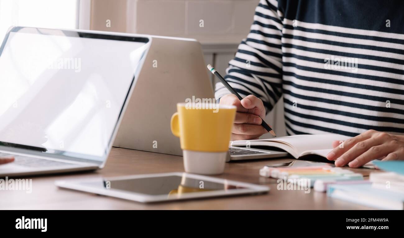 Close up of male student busy studying using laptop make notes in