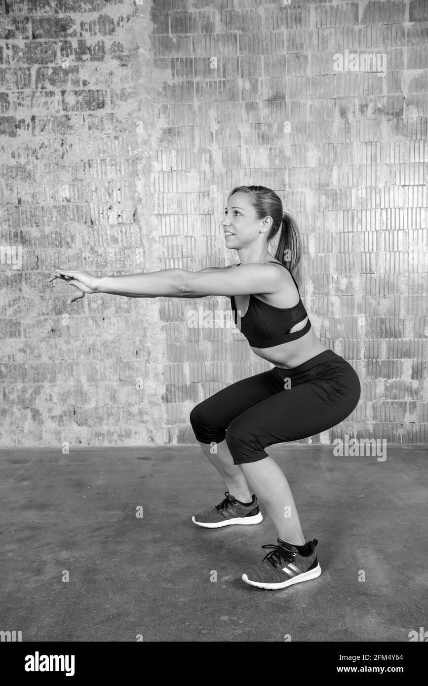 Concentrated european woman doing squats and workout indoors Stock Photo