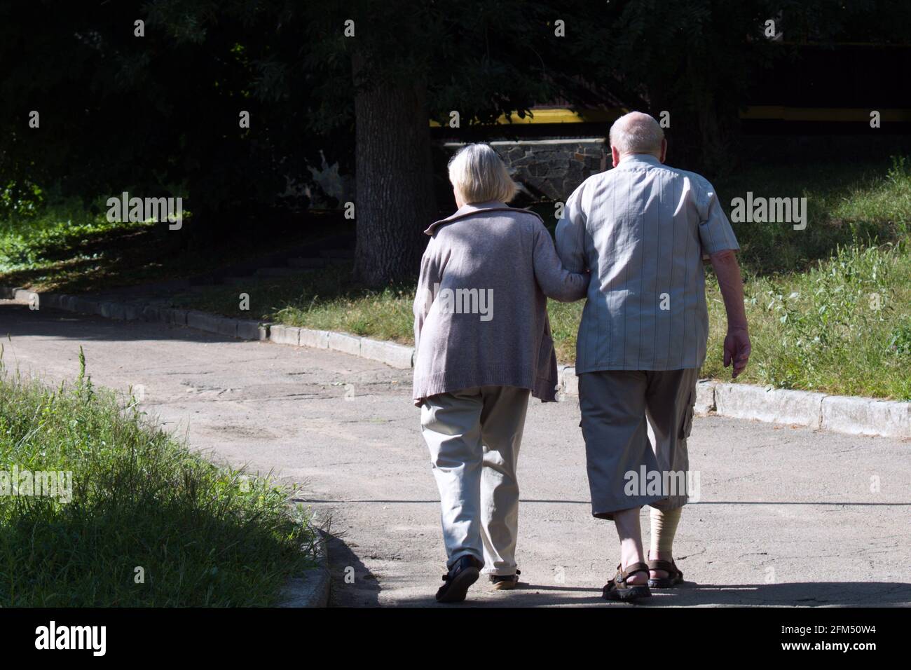 elderly man and woman walking down the path in park Stock Photo - Alamy