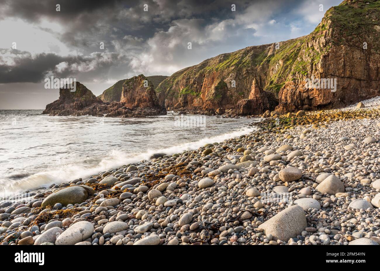 Shingle beach surrounded by rocky cliffs and sea stacks in a bay near Bloody Foreland, County Donegal, Ireland Stock Photo