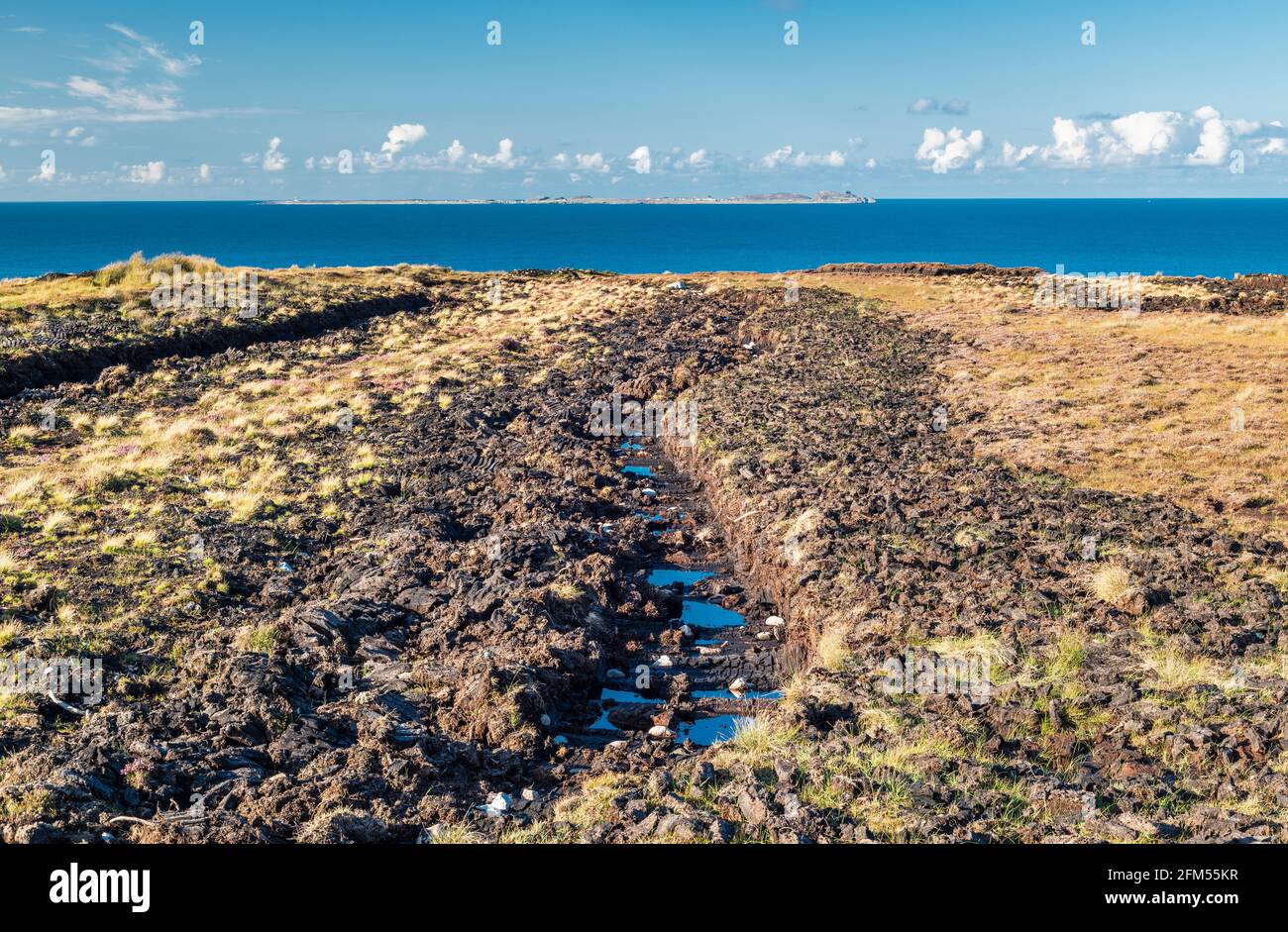 Cut peat bog with sods of turf cut for fuel, left out to dry, near Bloody Foreland, County Donegal, with Tory Island in the background Stock Photo