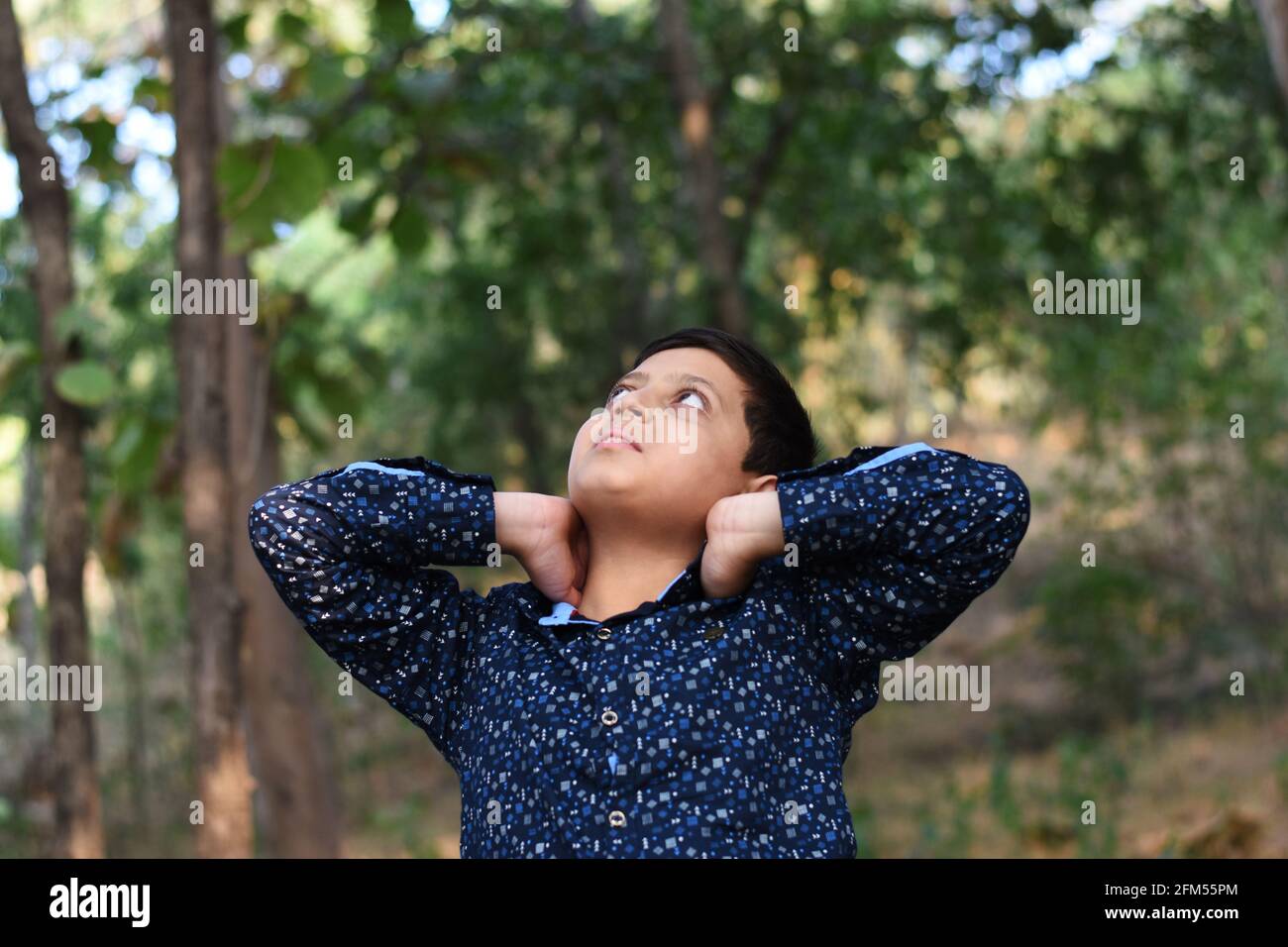 Young boy with hands on neck looking up Stock Photo