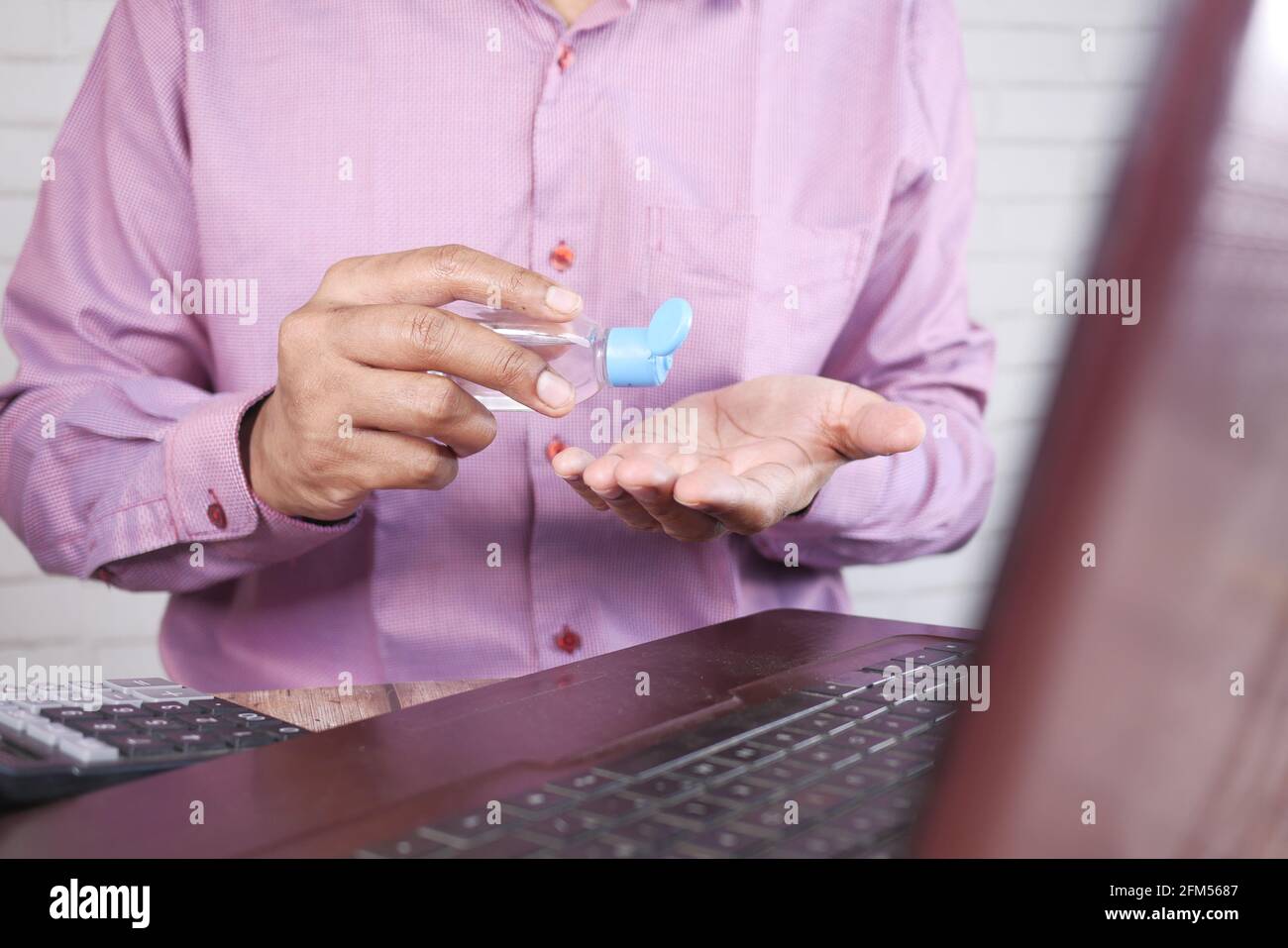 young man applying sanitizer liquid before using laptop Stock Photo - Alamy