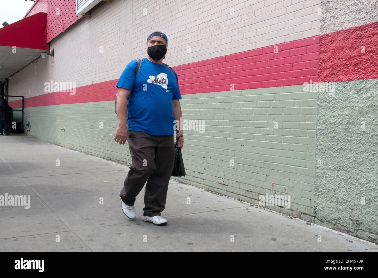 A man wearing a mask and a Mets tee shirt out shopping in Corona, Queens, New York City. Stock Photo