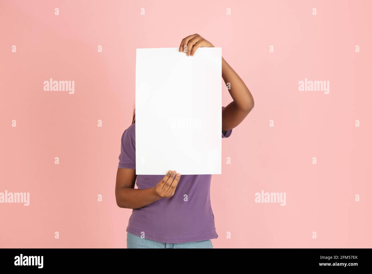 Portrait of African woman with blank sheet of paper isolated on pink ...
