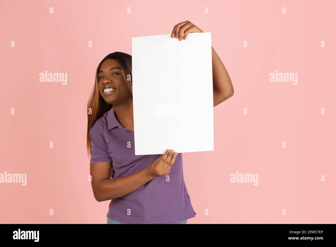 Portrait of African woman with blank sheet of paper isolated on pink ...