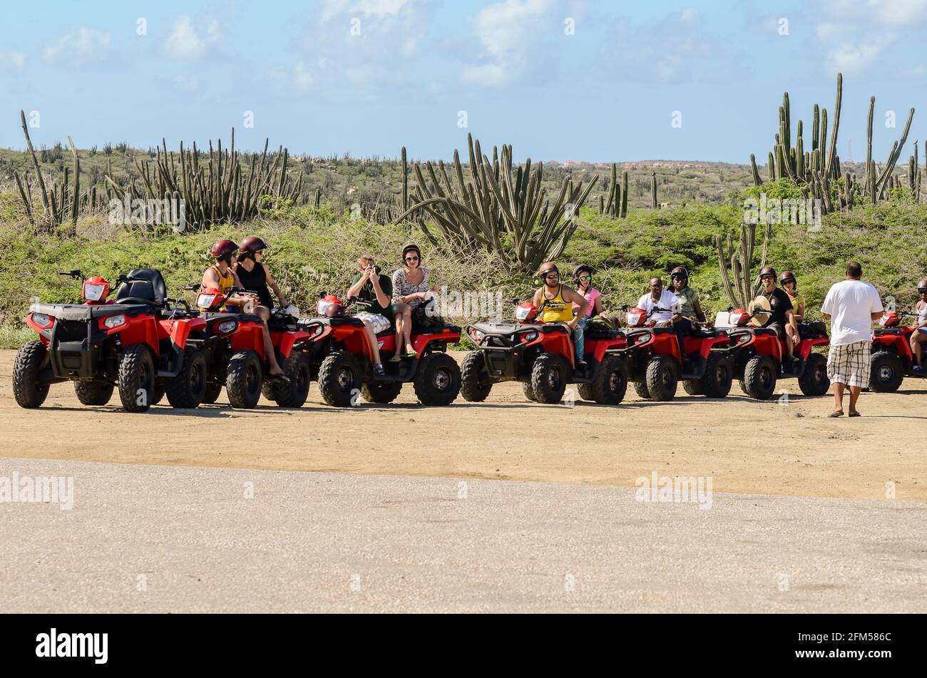 Group of people having a guided tour by some quads with some cacti in the background in Aruba Stock Photo