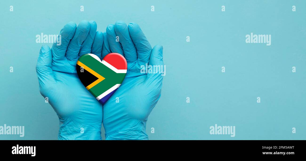 Doctors hands wearing surgical gloves holding South Africa flag heart Stock Photo
