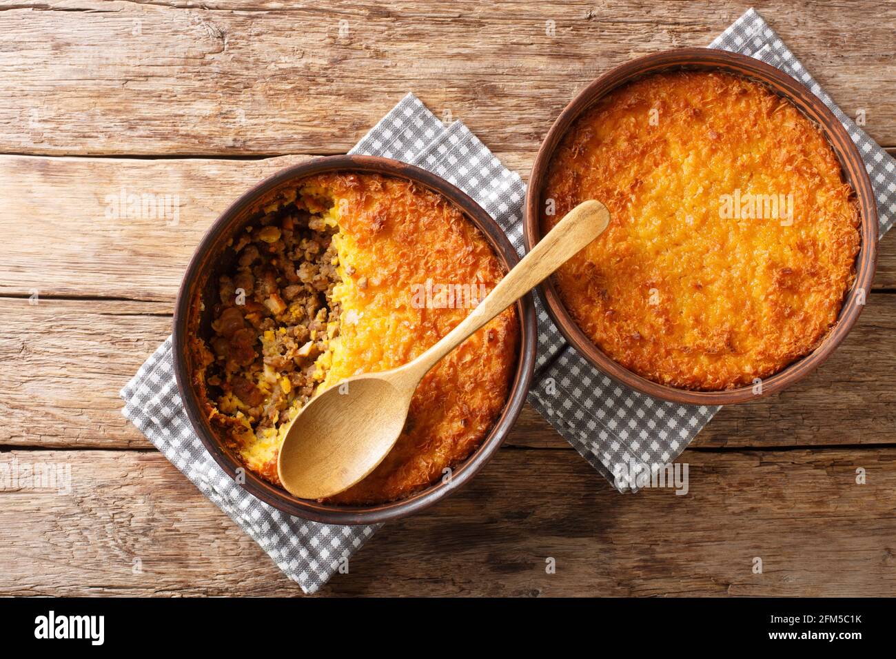Pastel de choclo corn pie is a Chilean dish based on sweetcorn and beef closeup in the pots on the table. Horizontal top view from above Stock Photo