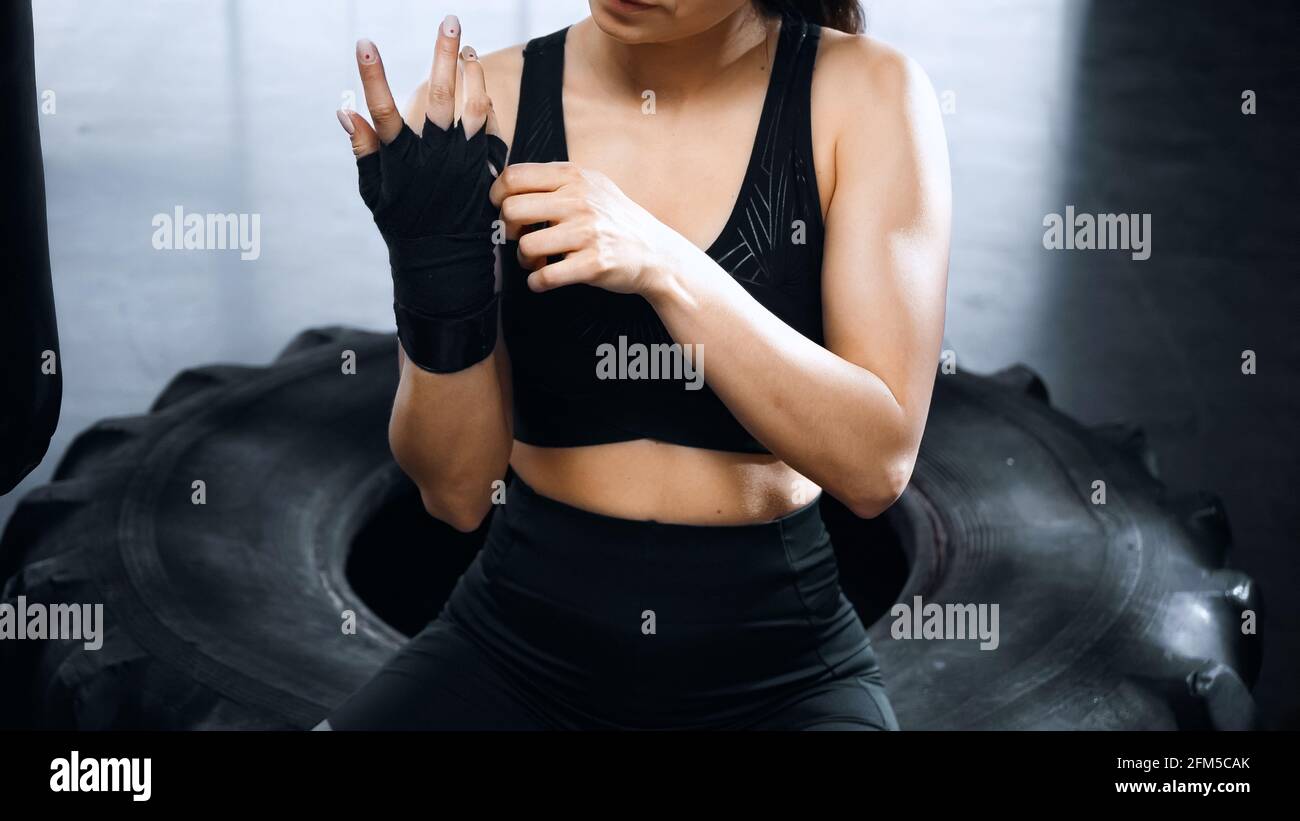 cropped view of young sportswoman putting on hands boxing bandages Stock Photo
