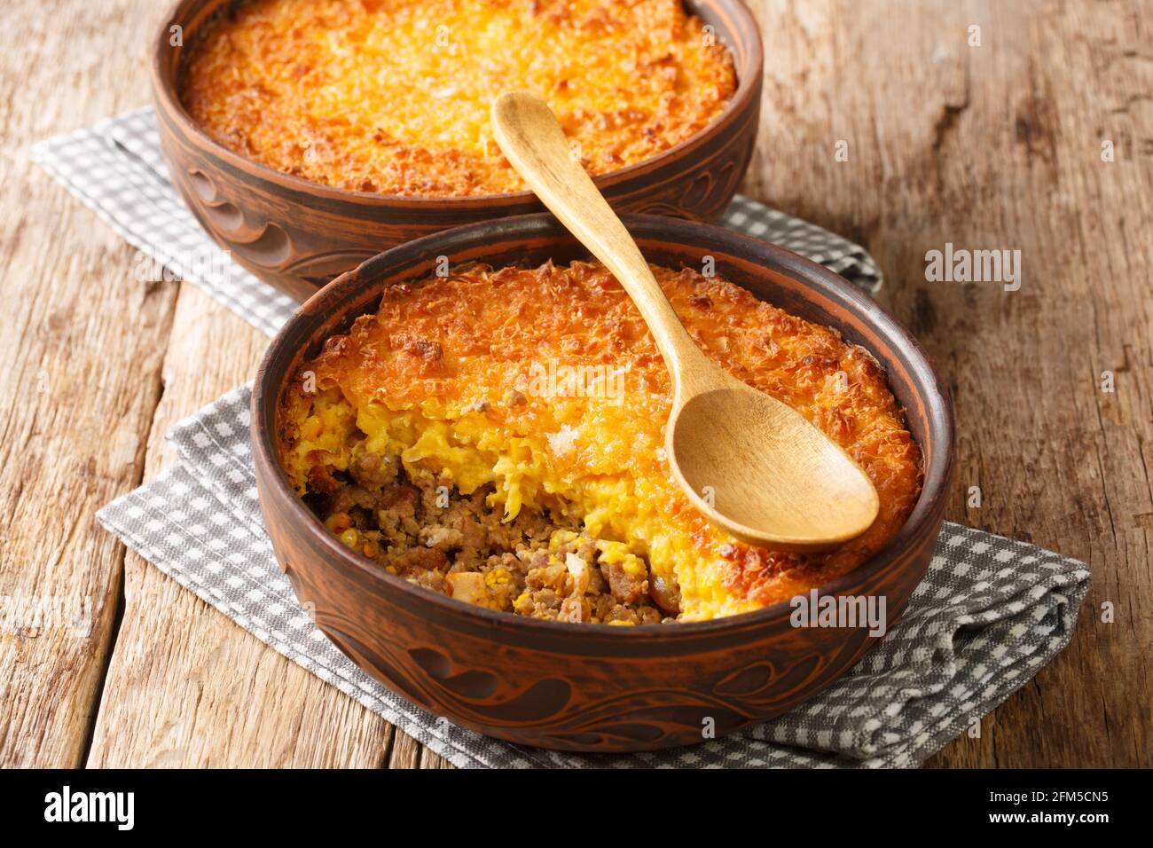 Chilean shepherd's pie, pastel de choclo tops spiced ground beef with a pureed corn crust closeup in the pots on the table. Horizontal Stock Photo