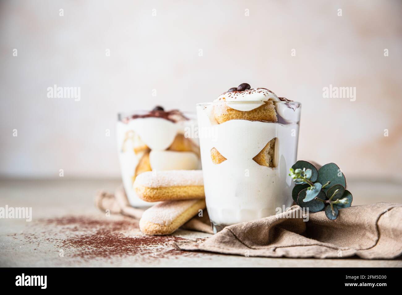 Traditional Italian dessert tiramisu in glass, light stone background