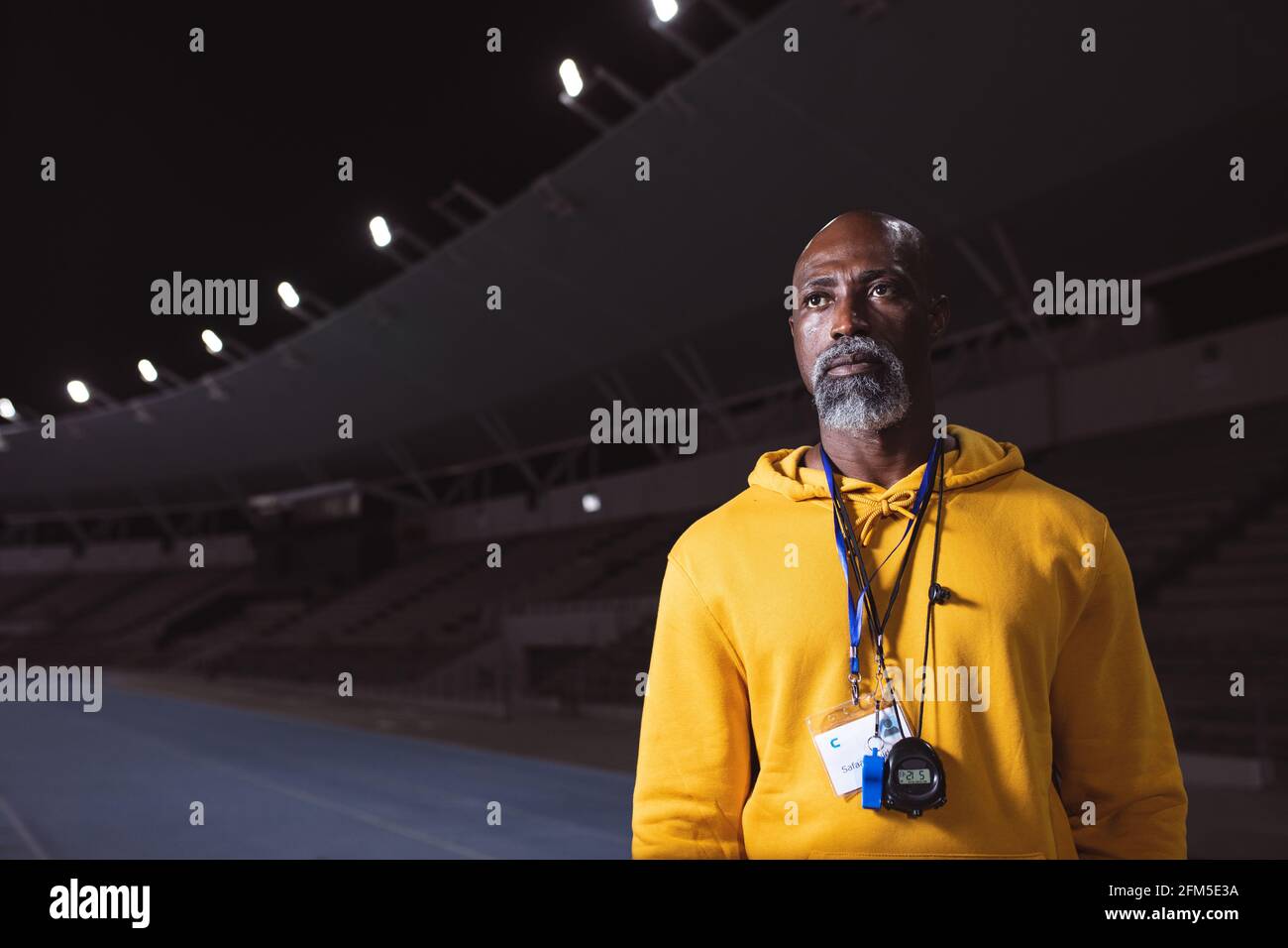 African american senior male coach standing on the running track at