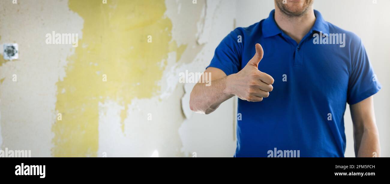 house renovation service - construction worker, handyman with thumb up gesture standing in old room. copy space Stock Photo