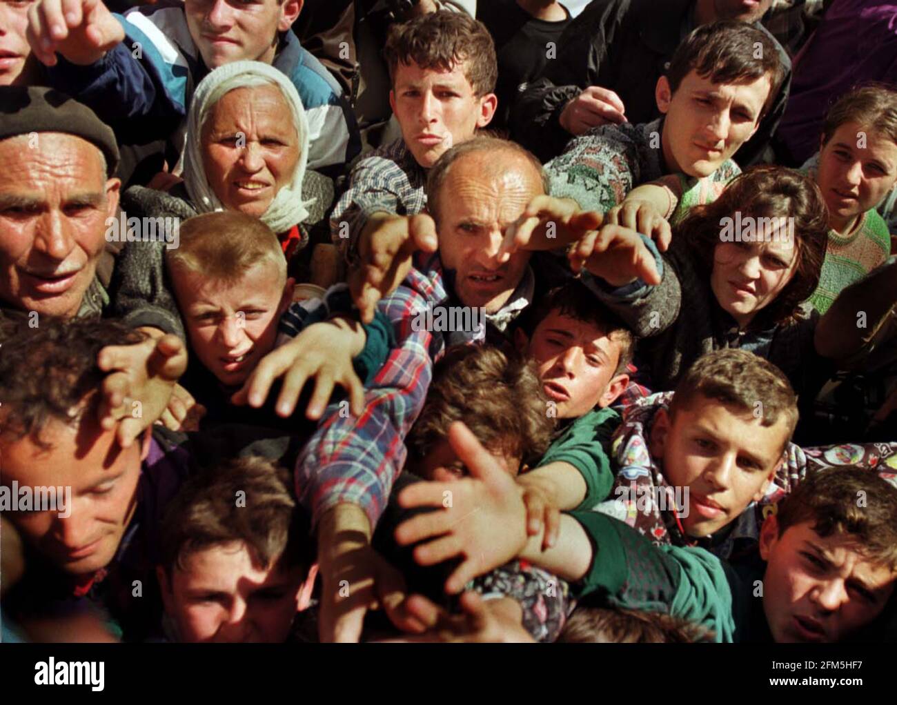 Newly arrived refugees desperately fight for UNHCR rations at the Albanian border. Stock Photo
