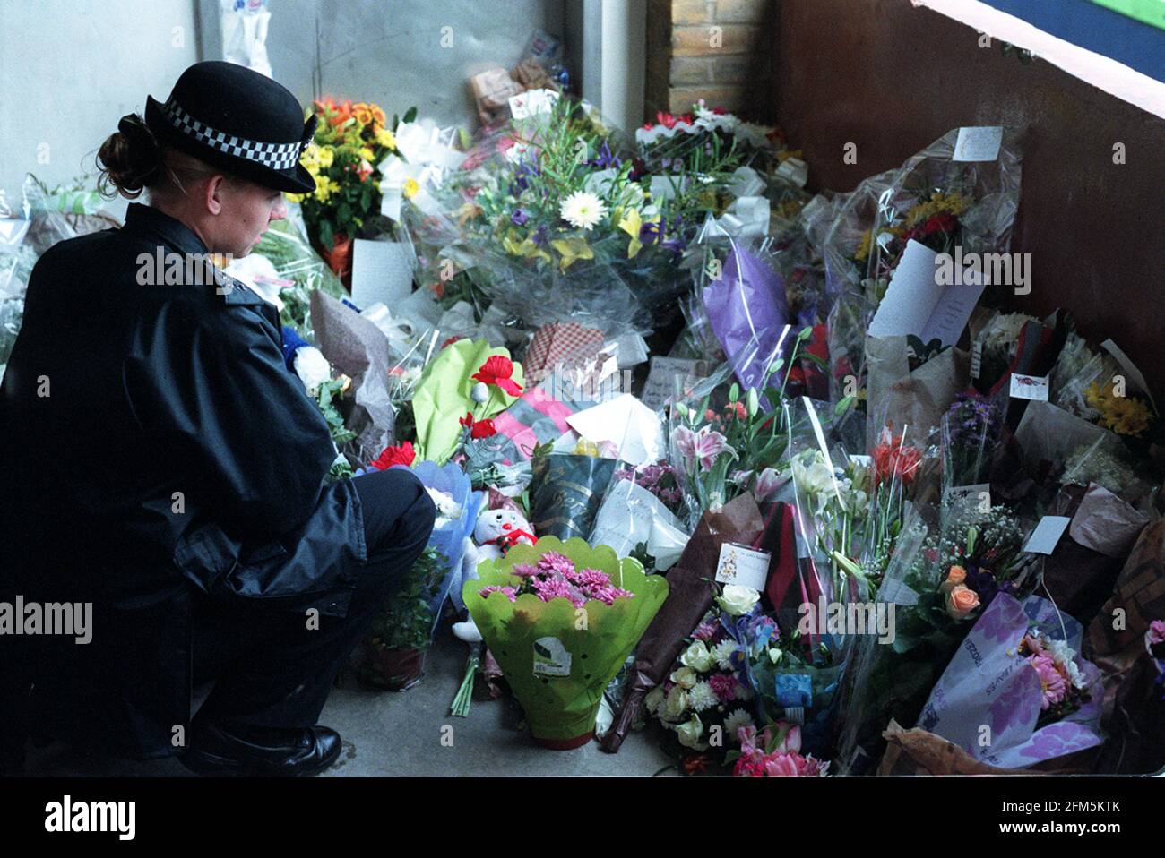 A POLICEWOMEN ON DUTY DECEMBER 2000 AT THE SCENE OF DAMILOLA TAYLOR'S MURDER, IN PECKHAM, LOOKING AT THE FLORAL TRIBUTES Stock Photo