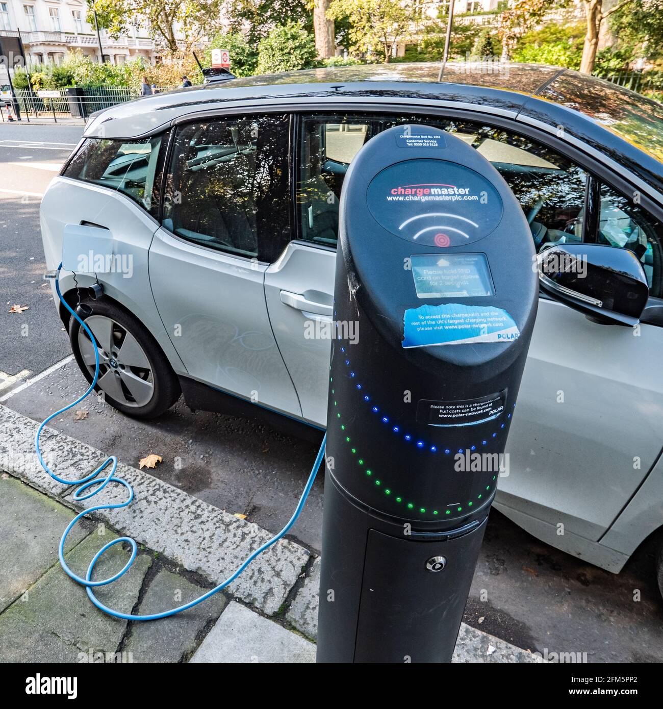 Electric car charging point. An electric car plugged into a public